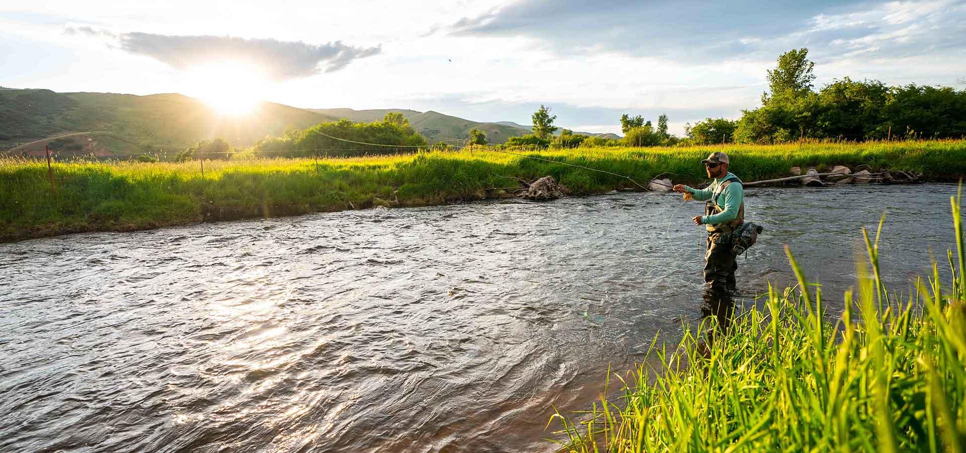 Jans Expert fly fishing with the sun setting over a ridge in the background on a river near Park City, UT.