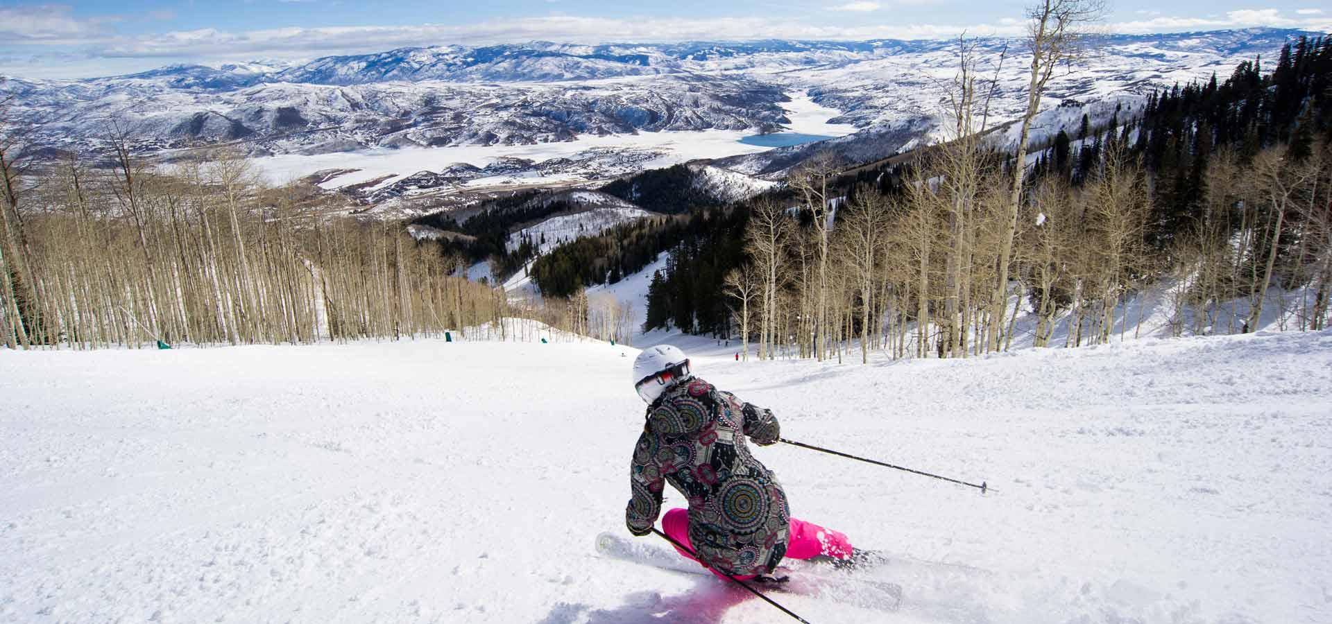 A skier descends a slope toward the Jordanelle Reservoir at Deer Valley in Park City, UT