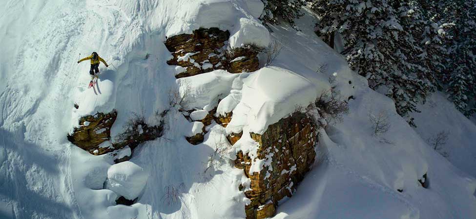 Skier jumping off a large cliff in the backcountry.