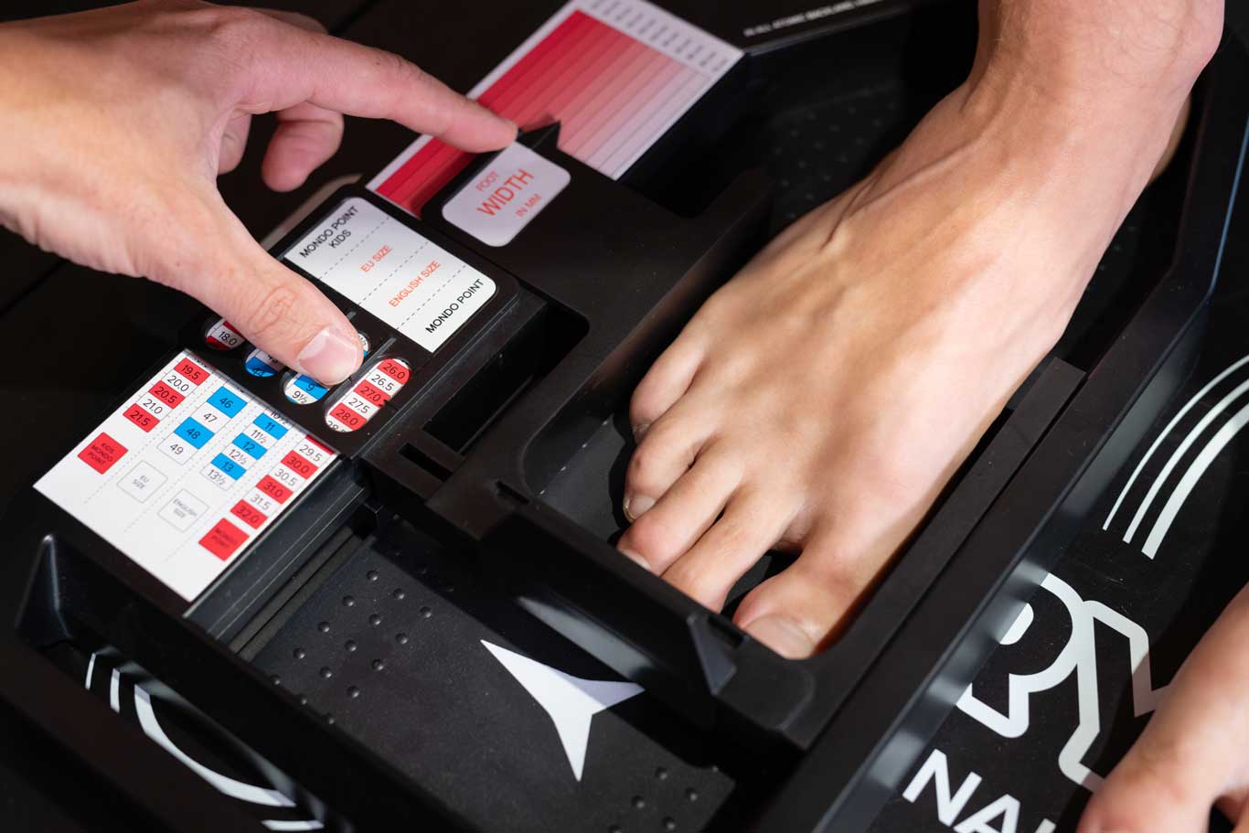Bootfitter measuring the last width of a client’s foot.
