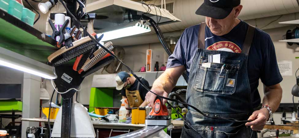 Jans Expert Andy Buckley uses a waxing iron to melt wax onto a pair of skis.