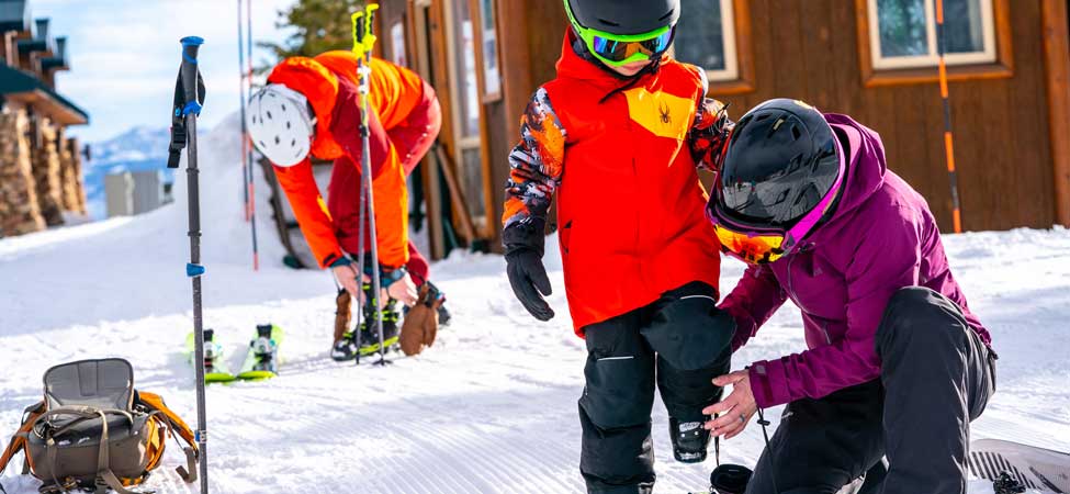 Woman helps her son put on his skis at Deer Valley Resort in Park City, Utah.