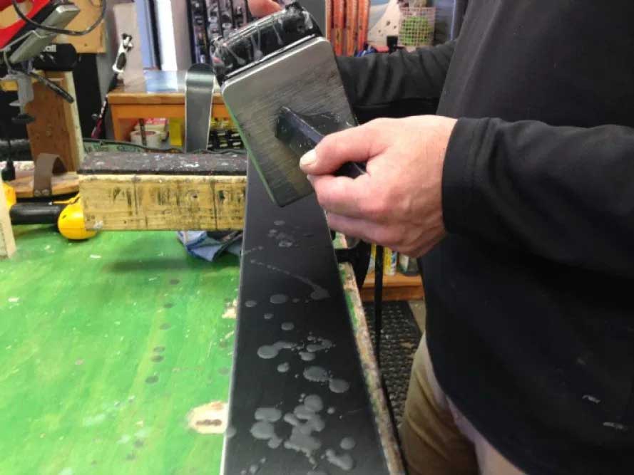 Dripping wax using a waxing iron onto the bases of a pair of skis.