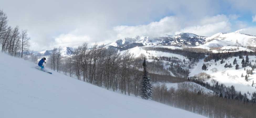Jans Expert Jack Walzer skis down a run at Deer Valley Resort with the Park City mountains in the background.