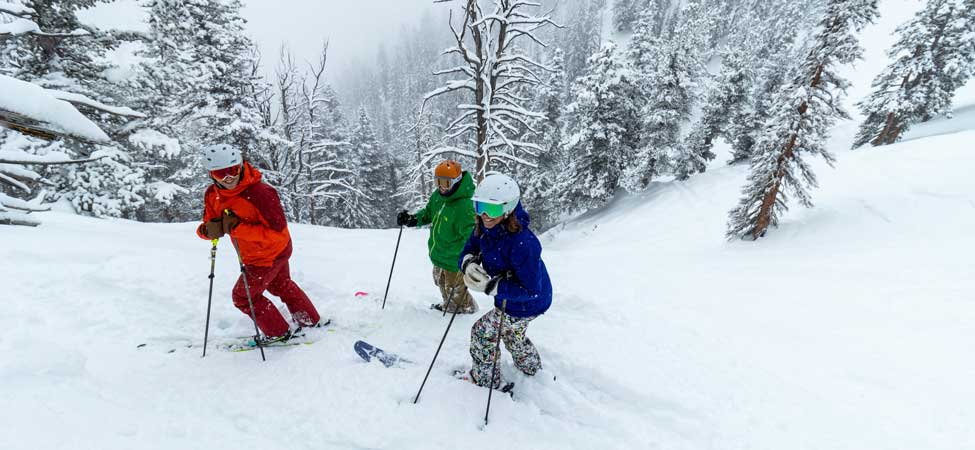 Three skiers stand at the top of a run at Solitude Mountain Resort in Utah.