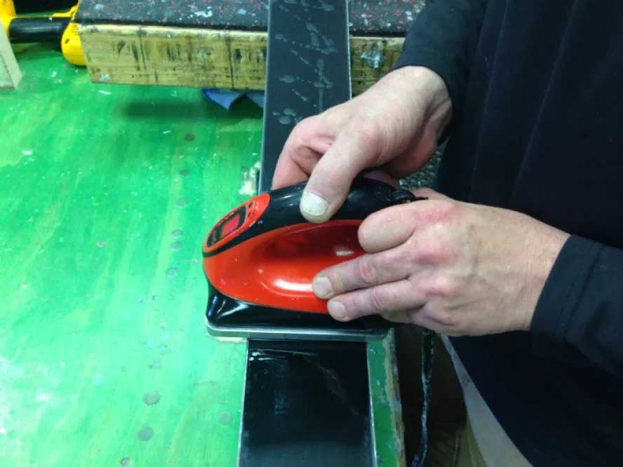 Melting wax onto the bases of a pair of skis using a waxing iron.