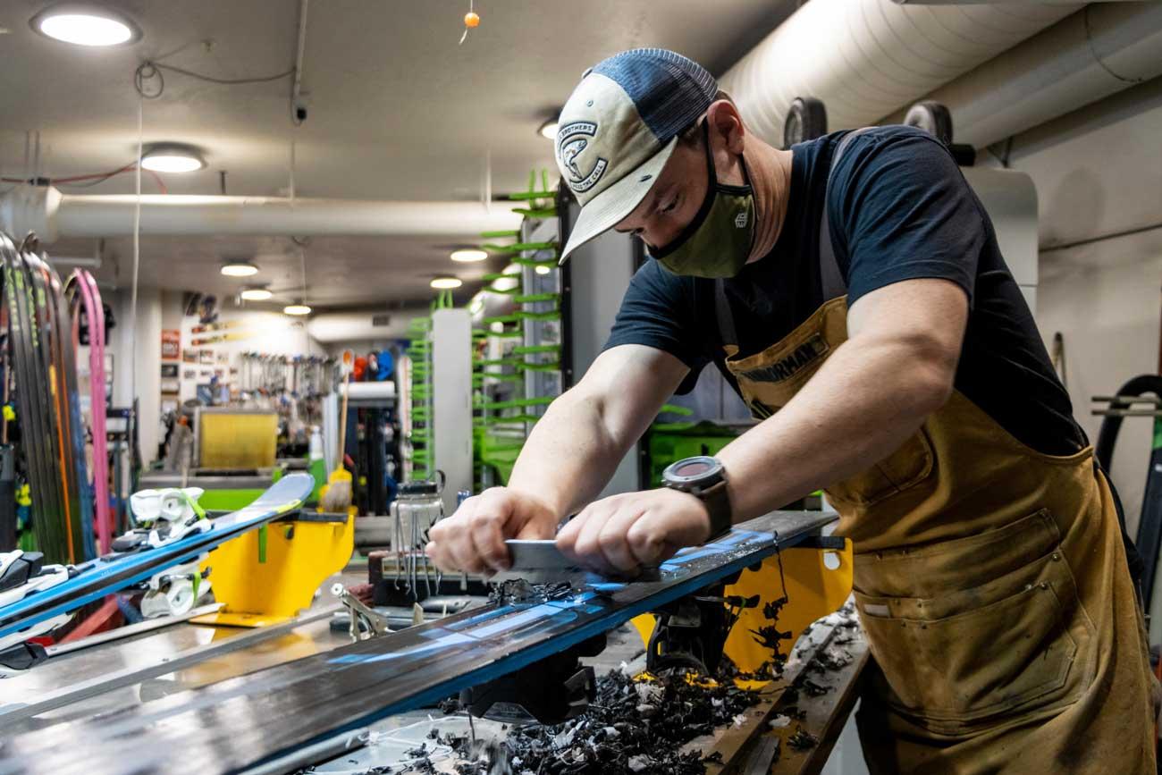 Ski technician scrapes excess wax off of a pair of skis at Rennstall in Park City, Utah.