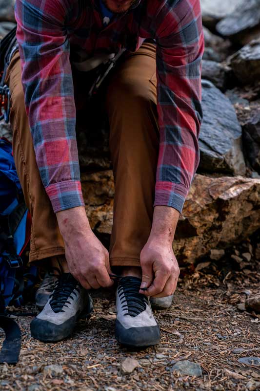 A climber lacing up their climbing shoes before starting up a route in Big Cottonwood Canyon, Utah.