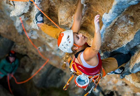A climber on a sport route is secured to their rope by their harness. Image courtesy of Petzl.