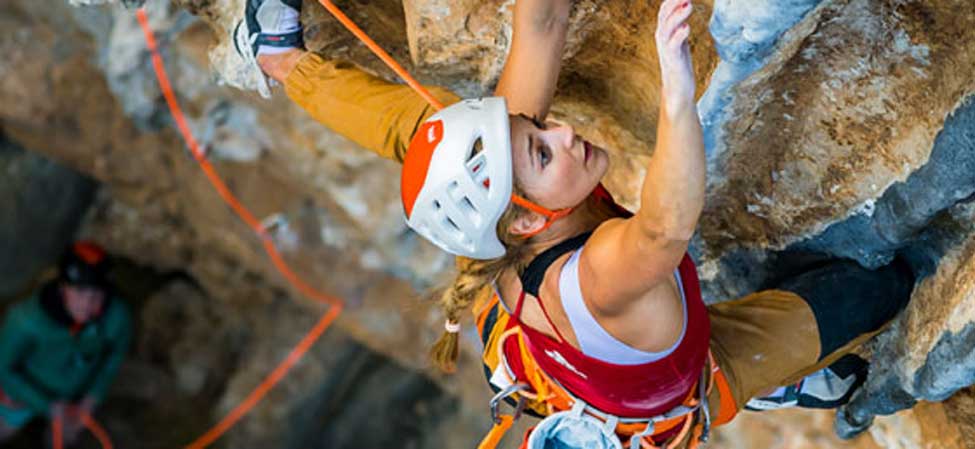 A climber on a sport route is secured to their rope by their harness. Image courtesy of Petzl.