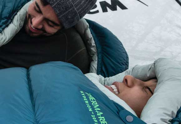 Campers staying warm in their sleeping bags at sunrise. Image courtesy of Thermarest.