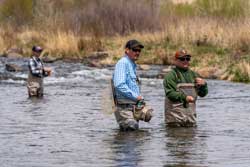 fly fishing guide puts net away, while his client holds the fish he just caught
