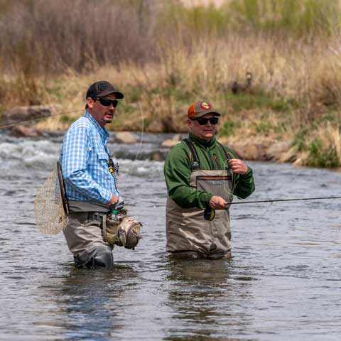 Jans fly fish guide helps a client with their casting on a fly fishing trip.