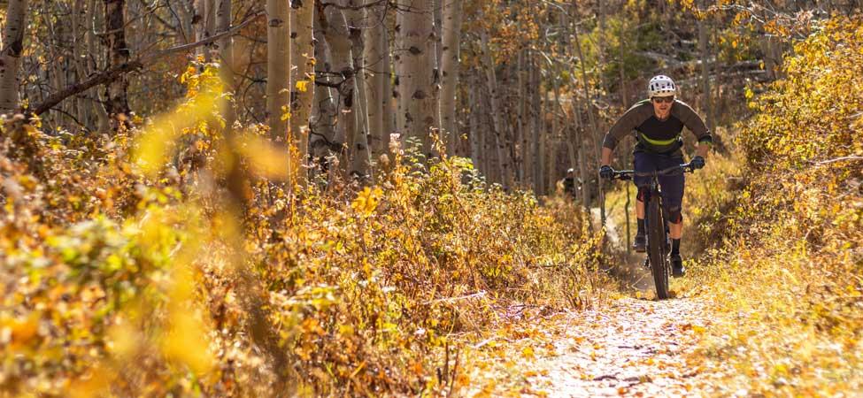 A mountain biker rides through golden fall leaves on a trail in Park City, UT.