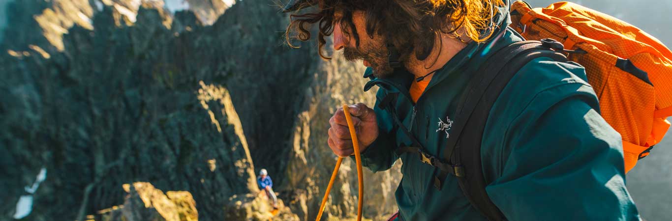 A climber on an exposed wall looks down at his climbing partner